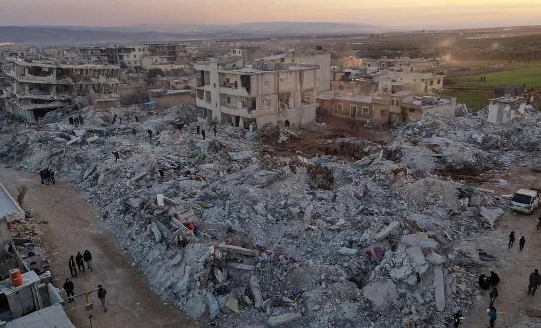 Varias personas caminan junto a edificios colapsados el jueves 9 de febrero de 2023 en Jinderis, en la provincia de Alepo, Siria, luego de un terremoto. Foto: Ghaith Alsayed/AP