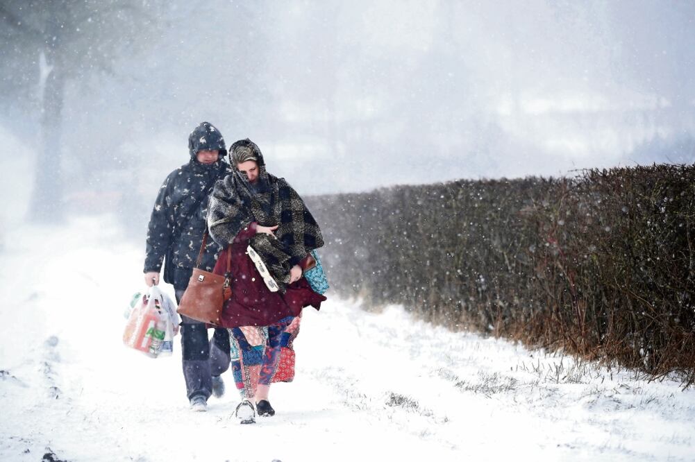Una pareja camina en medio de una fuerte nevada después de haber tenido que abandonar su auto ante la acumulación de nieve en la localidad de Leek, en Inglaterra (CARL RECINE. REUTERS)