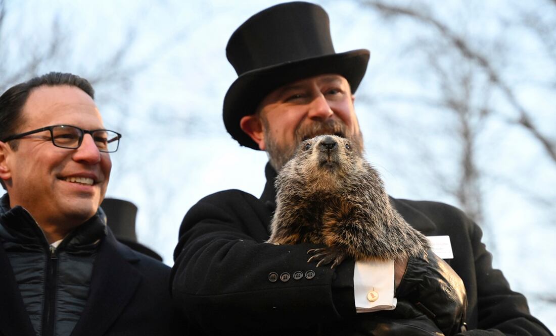 El manejador del Groundhog Club A.J. Dereume sostiene a Punxsutawney Phil mientras que el gobernador de Pensilvania, Josh Shapiro, observa durante la celebración número 137 del Día de la Marmota en Gobbler's K. Foto: AP