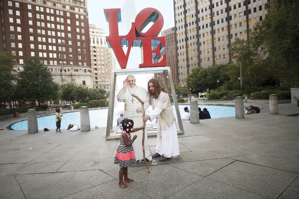 Un hombre disfrazado de Jesucristo interactúa con una niña, junto a una figura del Papa en Filadelfia, EU, donde estará Francisco en unos días (MARK MAKELA. REUTERS)