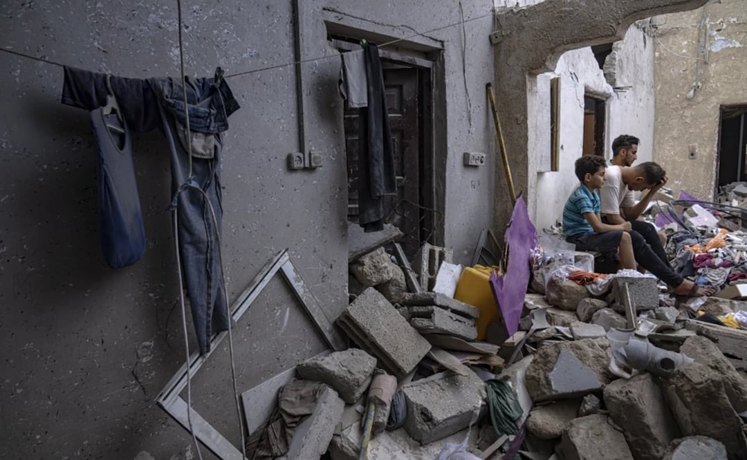 Palestinos sentados entre los escombros de una casa después de que fuera alcanzada por un bombardeo israelí en Khan Younis, en el sur de la Franja de Gaza. Foto: AP