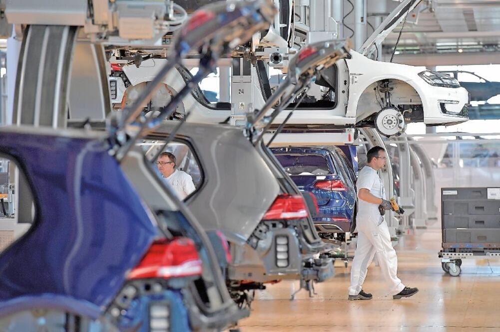 Mecánicos en la línea de producción del e-Golf en la planta de Dresden, Alemania. La empresa Faurecia está a punto de cerrar un contrato con Volkswagen para la proveeduría de esa línea de autos (MATTHIAS RIETSCHEL. REUTERS)