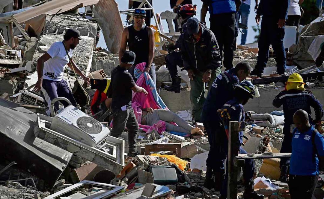 Equipos de rescate y residentes cubren un cuerpo entre los escombros en Catia La Mar, La Guaira. Foto: AFP