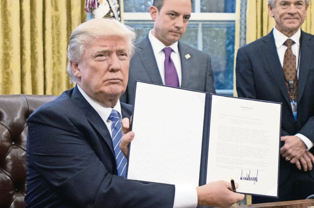 El presidente Donald Trump muestra la orden ejecutiva firmada ayer en la Oficina Oval, la cual establece el retiro de Estados Unidos del TPP. (RON SAC. XINHUA)