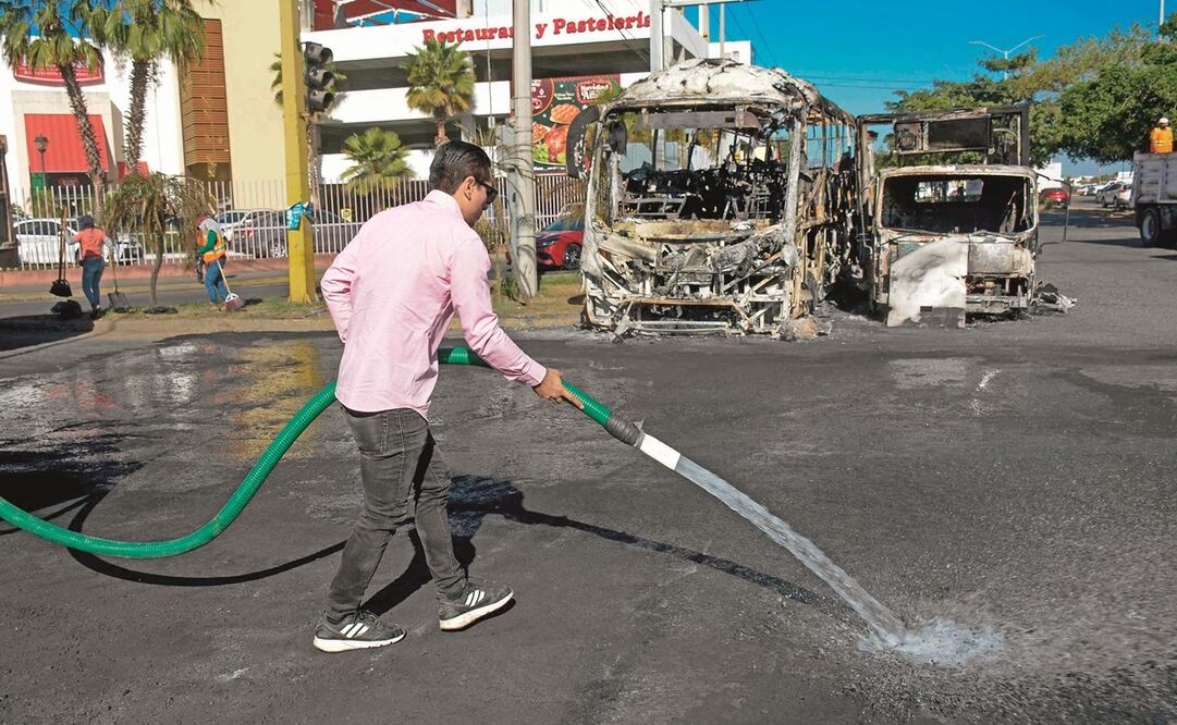 Ciudadanos limpian las calles, luego de los destrozos provocados por la quema de vehículos en varios puntos de Sinaloa. Foto: Juan Carlos Cruz / AFP