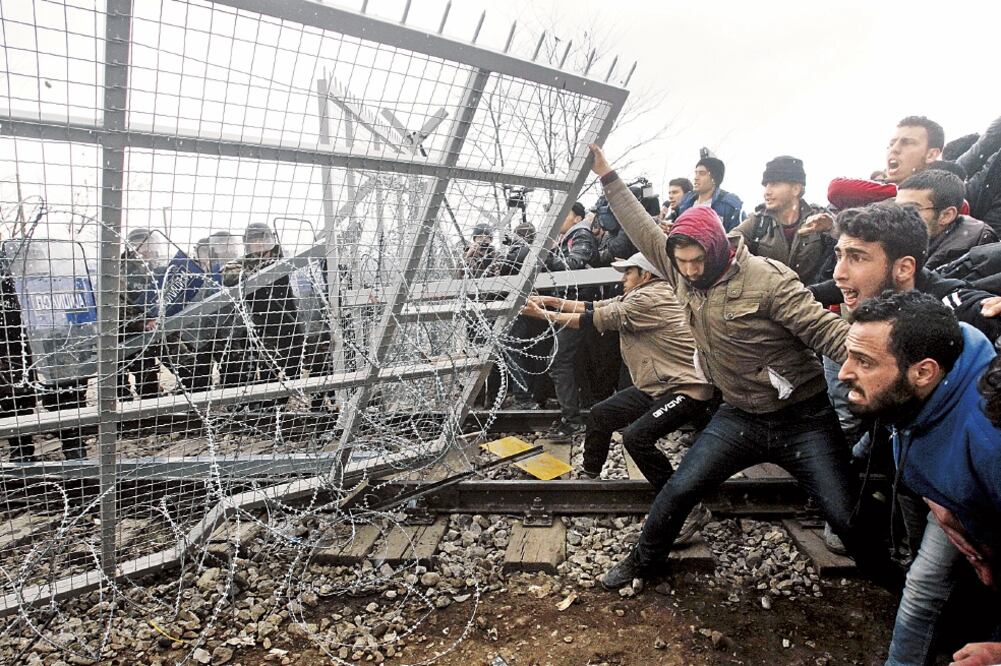Migrantes que quedaron varados rompen la valla que divide la frontera entre Grecia y Macedonia, cerca de la villa griega de Idomeni (ALEXANDROS AVRAMIDIS. REUTERS)