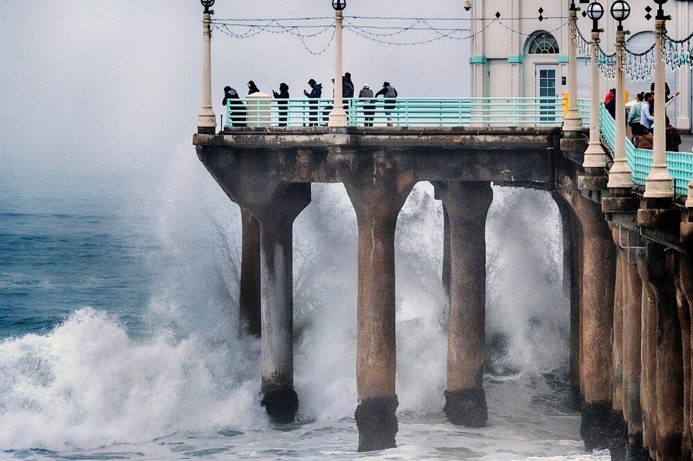 La gente se para al final del muelle de Manhattan Beach y observa cómo el oleaje golpea las torres de alta tensión el martes 24 de diciembre de 2024 en Manhattan Beach, California. Foto: AP