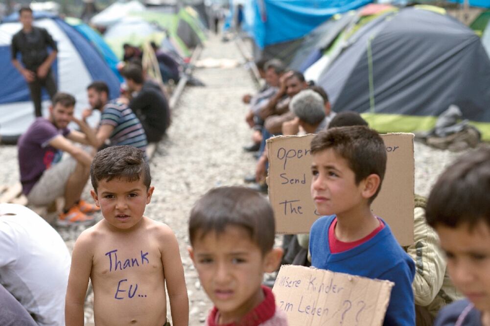 Niños con pancartas agradeciendo a la UE por recibirlos y pidiendo no los devuelvan a sus países de origen, durante una protesta realizada el jueves en un campo de refugiados en Idomeni, Grecia (PETROS GIANNAKOURIS. AP)