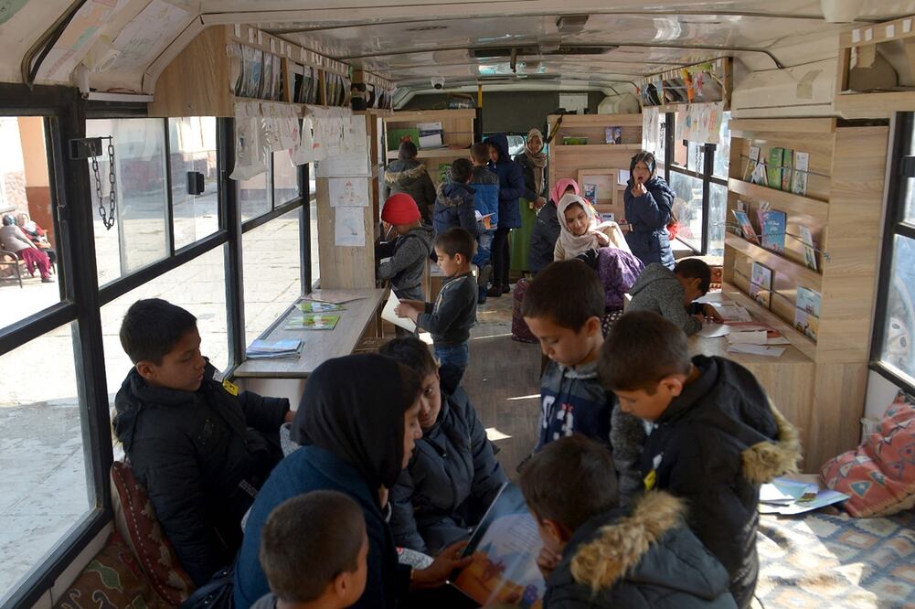 Estudiantes afganos consultan libros de la biblioteca móvil. Foto: AFP / Ahmad Sahel Arman