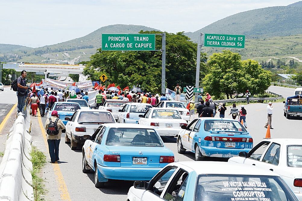 En esta imagen de 2014, integrantes de la Coordinadora Estatal de Transportistas Independientes de Guerrero (CETIG) bloquean la Autopista del Sol para protestar por la entrega de concesiones en la entidad, porque aseguran que se favorece a grupos vinculad
