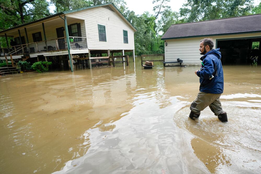 Hombre camina entre las aguas mientras se dirige a su casa, el viernes 3 de mayo de 2024, en New Caney, Texas. (Brett Coomer/Houston Chronicle vía AP)