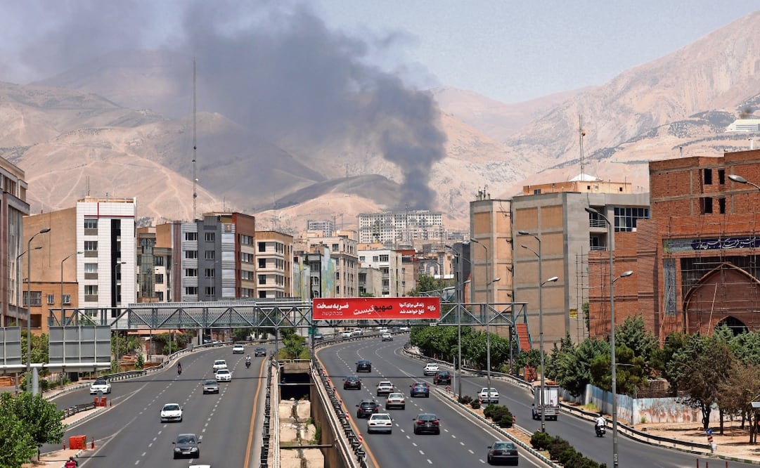 Autos circulan por una autopista mientras se eleva humo al fondo desde una refinería de petróleo, en el noroeste de Teherán, Irán. Foto: Abedin Taherkenareh / EFE