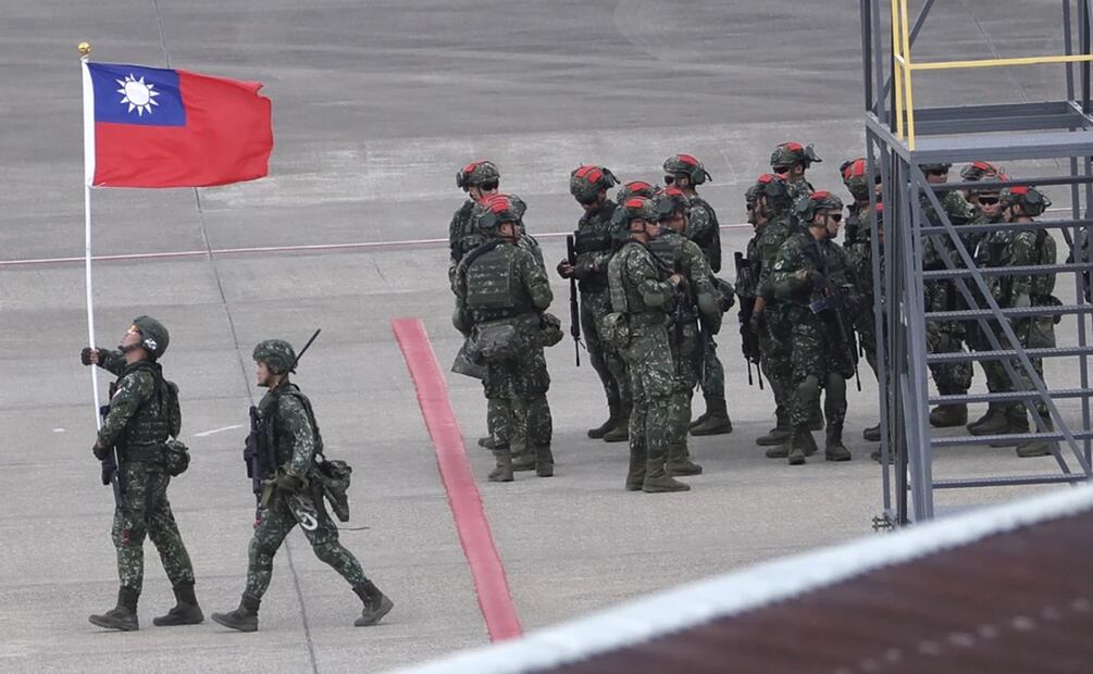 Un soldado taiwanés sostiene una bandera de Taiwán cerca de un grupo de soldados con marcas rojas en sus cascos porque se harán pasar por enemigos durante las maniobras anuales Han Kuang. Foto: AP