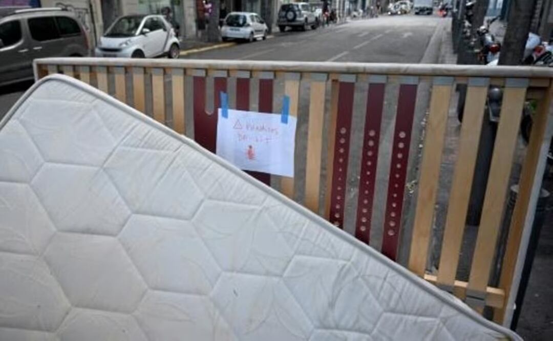 Esta fotografía muestra un colchón y un somier con un cártel pegado indicando "chinches", abandonados en una calle de Marsella. Foto: AFP