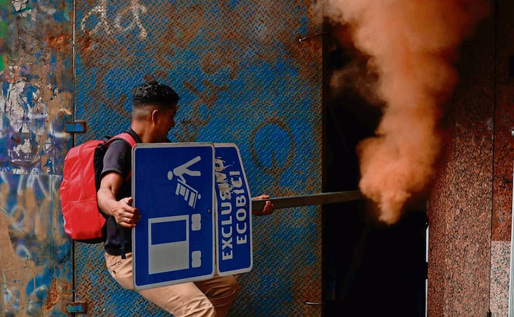 Con el tubo de una señal arrancada de la calle, un hombre intentaba tapar la salida del gas lacrimógeno que fue lanzado por un hoyo de las vallas. Foto: Diego Simón / EL UNIVERSAL