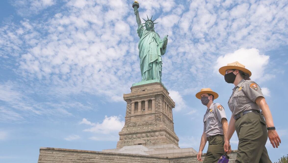 Rangers vigilan los alrededores de la Estatua de la Libertad, en la Isla de la Libertad, en Nueva York, que ayer reabrió sus puertas tras cerrar en marzo por la pandemia de coronavirus. JUSTIN LANE. EFE