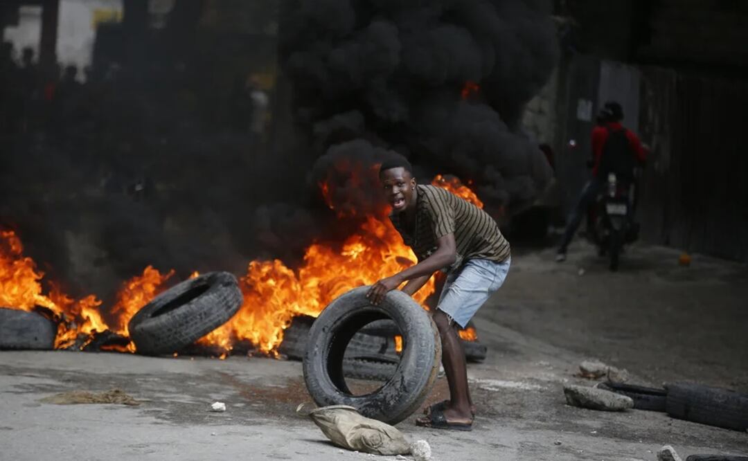 Un manifestante coloca neumáticos en una barricada en llamas durante una protesta para exigir la renuncia del primer ministro, Ariel Henry, en Puerto Príncipe, Haití. Foto: AP
