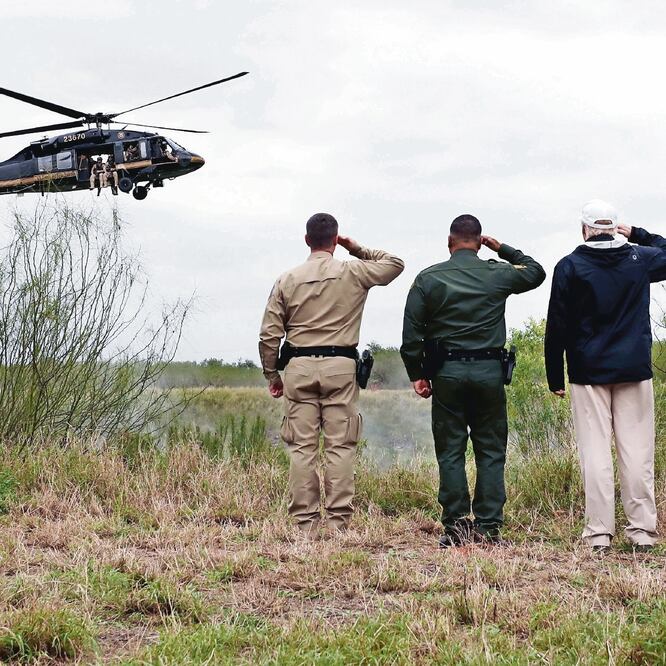 El presidente Donald Trump (der.), junto con otros dos oficiales saluda a un helicóptero y agentes de la Patrulla Fronteriza que sobrevuela la zona de Río Grande, Texas, en la frontera entre México y Estados Unidos, el pasado 10 de enero. REUTERS 