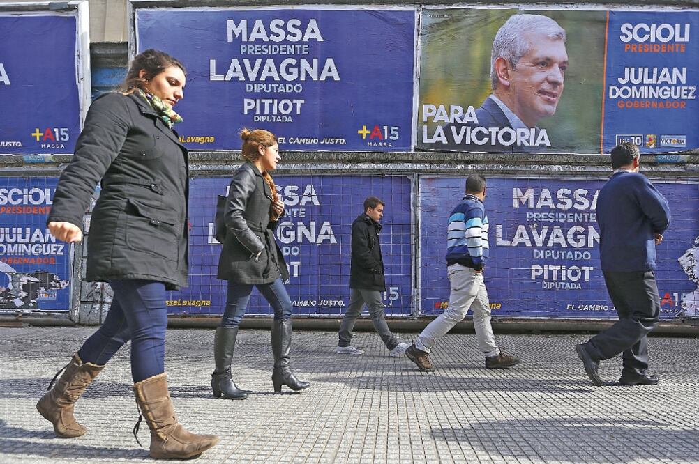 Transeúntes caminan frente a vallas con propaganda electoral en el centro de Buenos Aires, en vísperas de las primarias del domingo para elegir a los candidatos presidenciales argentinos (DAVID FERNÁNDEZ. EFE)