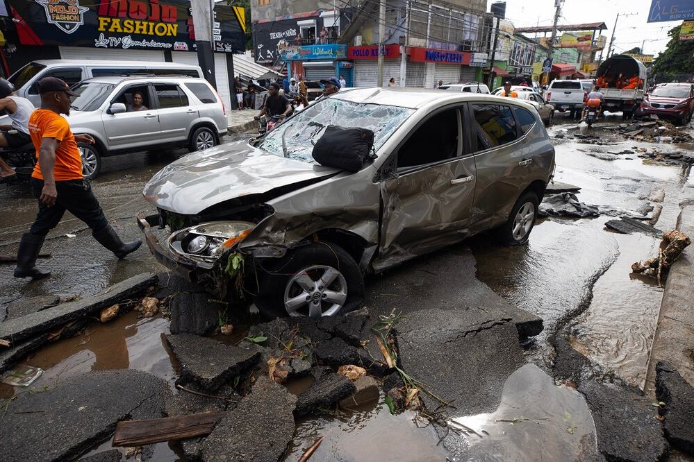 Un hombre camina junto a varios vehículos que fueron arrastrados por la corriente, en Santo Domingo. FOTO: ORLANDO BARRÍA. EFE