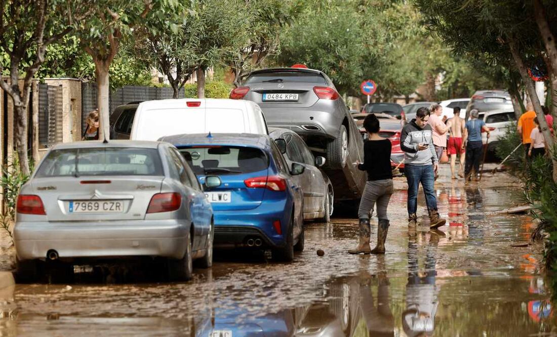 Varias personas junto a vehículos dañados por las intensas lluvias de la fuerte dana que afecta especialmente el sur y el este de la península ibérica, este miércoles en Picaña (Valencia). Foto: EFE