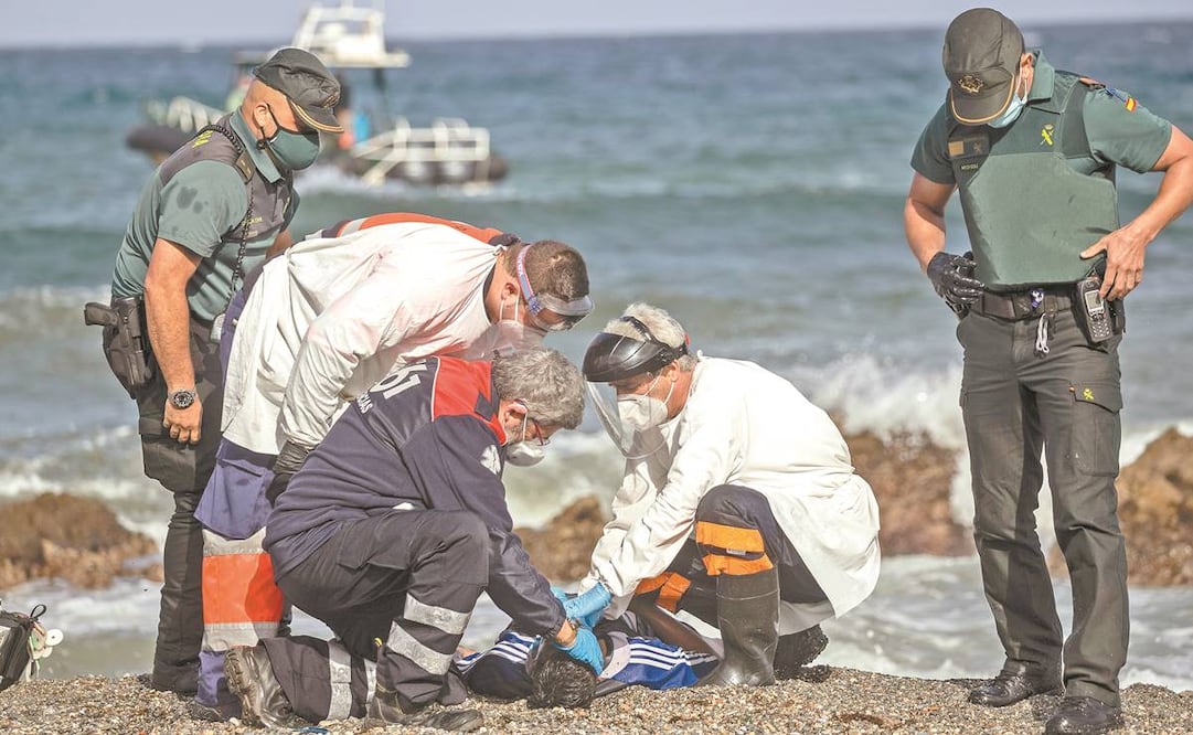 Médicos e integrantes de la Guardia Civil española revisan el cadáver de un joven en Ceuta. Foto: Bernat Armangue/ AP.
