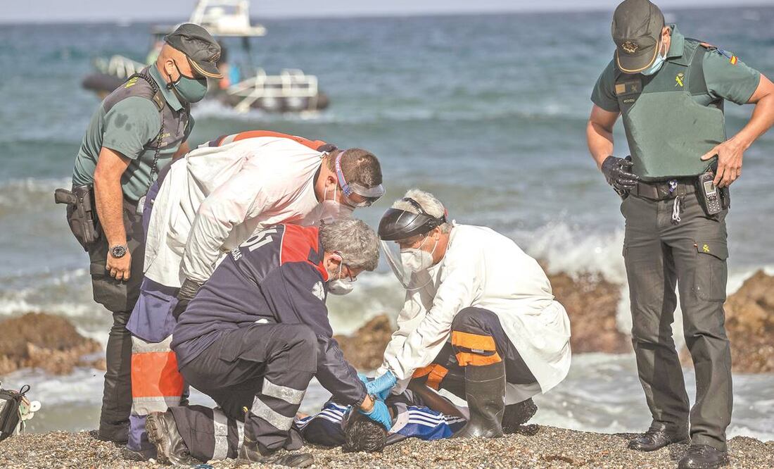 Médicos e integrantes de la Guardia Civil española revisan el cadáver de un joven en Ceuta. Foto: Bernat Armangue/ AP.