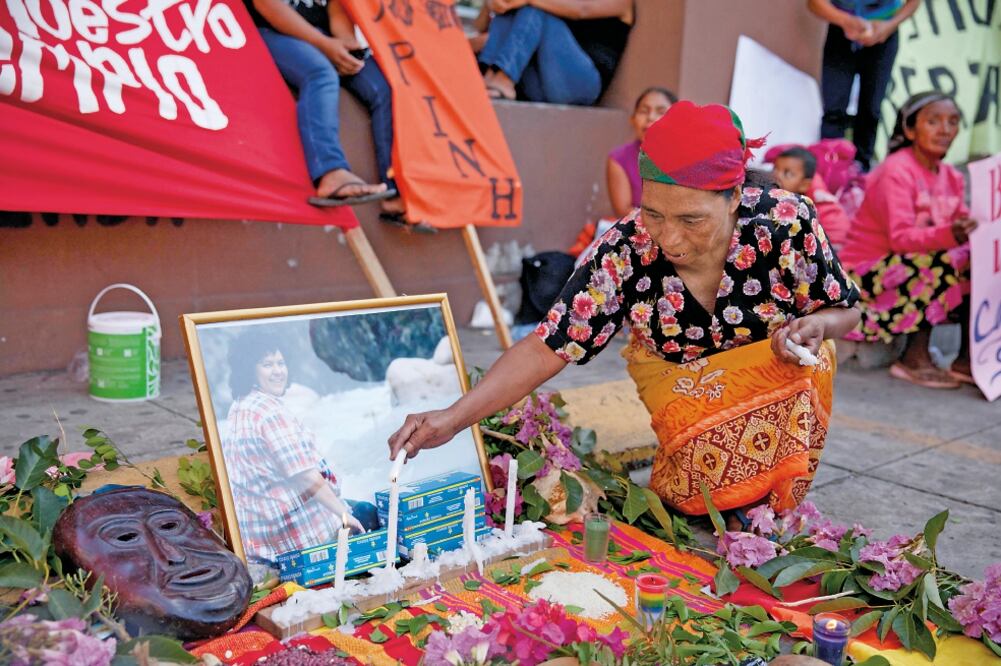 Una indígena hondureña coloca veladoras en un altar improvisado a Berta Cáceres colocado frente al Ministerio Público de Honduras, el martes. Activistas exigen el esclarecimiento del crimen (GUSTAVO AMADOR. EFE)