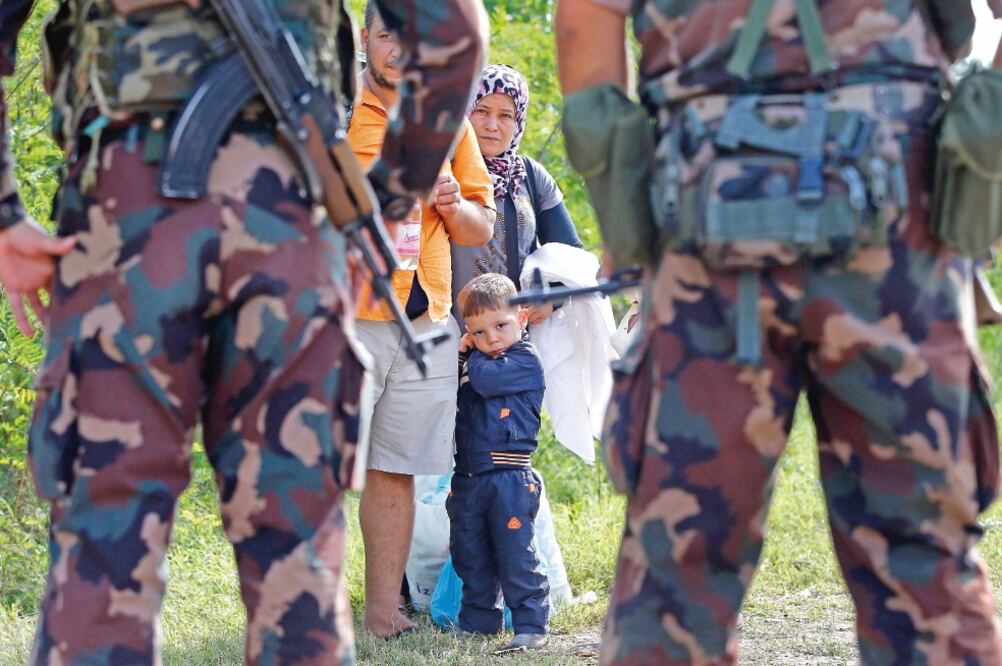 Soldados húngaros detienen a una familia de migrantes en la frontera entre Serbia y Hungría, en Asotthalom, cerca de Röszke (MATTHIAS SCHRADER. AP)