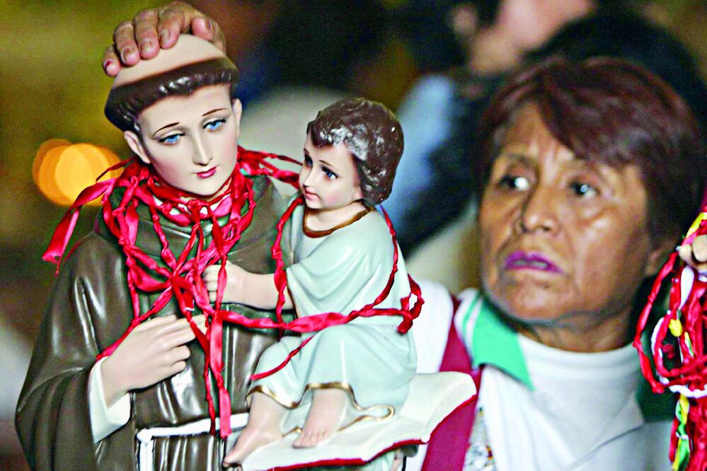 Mujeres recolectan de 13 monedas regaladas, una diaria, para pegarlas a un listón rojo y en otro anotarán su petición de conseguir pareja; ambos los cuelgan al santo (JUAN MANUEL BARRERA / EL UNIVERSAL)