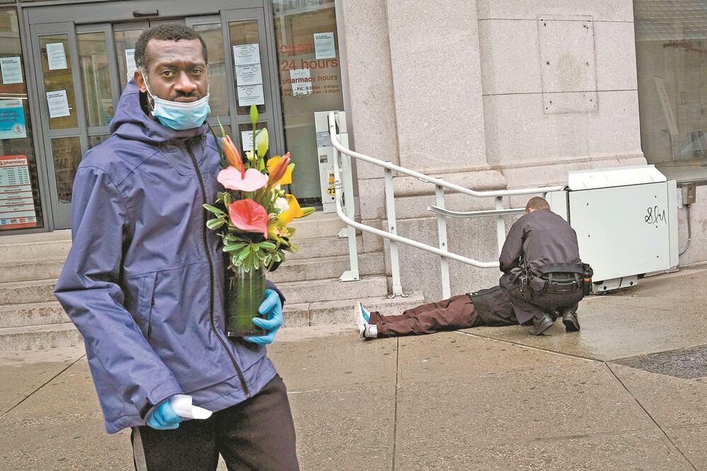 Un hombre pasa ayer junto a un oficial de policía que ayuda a una persona que está inconsciente en Nueva York, Estados Unidos. Foto: SPENCER PLATT. GETTY IMAGES