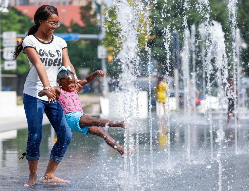 Aniya Huse, a la izquierda, le da una vuelta a su prima Heaven Reid, de 3 años, en una fuente de agua, el jueves 15 de junio de 2023, en Klyde Warren Park en Dallas. Foto: AP