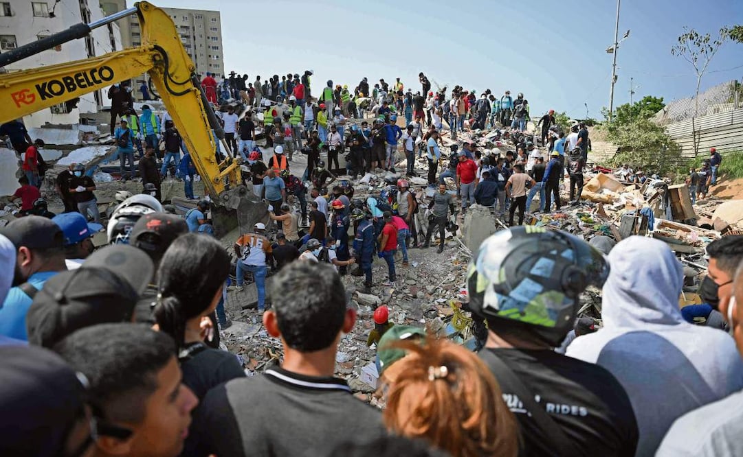 Equipos de rescate, voluntarios y residentes se reúnen alrededor de una excavadora mientras buscan entre los escombros de edificios colapsados en
Catia La Mar, La Guaira. Foto: Federico Parra / AFP