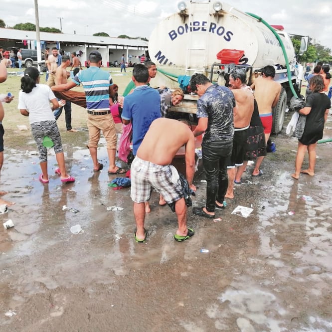 En las instalaciones de la Expo Feria de la Asociación Local Ganadera, los centroamericanos se arremolinan alrededor de las pipas de agua del Cuerpo de Bomberos para darse un baño y recuperar fuerzas. ÉDGAR ÁVILA. EL UNIVERSAL