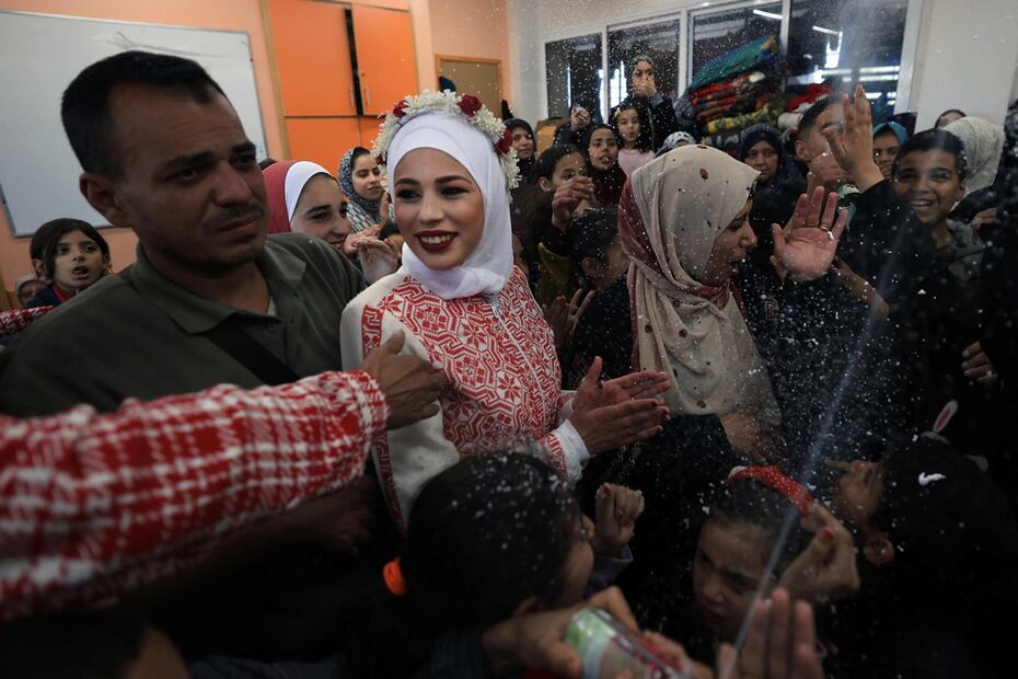 La pareja de recién casados ​​palestinos Afnan Yibril y Mustafa Shamlaj están rodeados de invitados y familiares durante su boda en la escuela de la UNRWA en el barrio de al-Salam de Rafah, en el sur de la Franja de Gaza. Foto: AFP