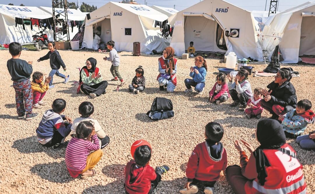 Niños sobrevivientes de los terremotos en Turquía juegan con personal de la Cruz Roja, en un campamento improvisado en Hatay. Foto: EFE