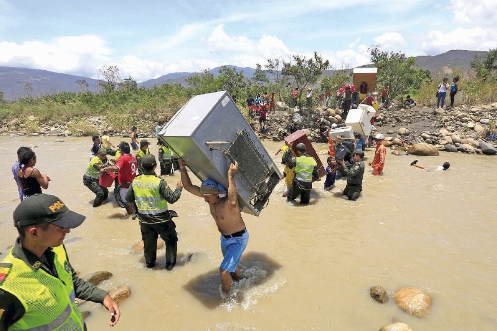Colombianos cargan sus pertenencias mientras cruzan el río Táchira, al regresar a su país y abandonar suelo venezolano (JOSÉ MIGUEL GÓMEZ. REUTERS)