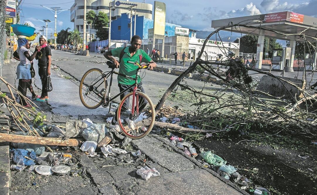 Un haitiano carga su bicicleta para poder cruzar una barricada, en Puerto Príncipe. Foto: Odelyn Joseph/ AP