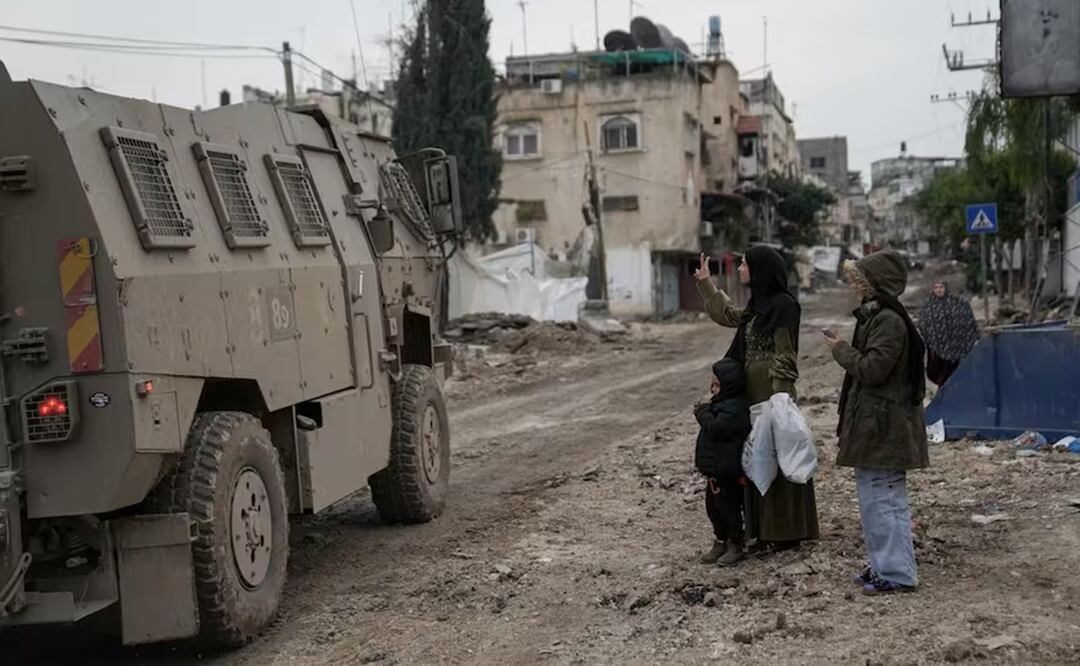 Una mujer palestina hace una "v" con sus dedos al paso de un vehículo militar israelí durante una redada en el campo de refugiados de Tulkarem, en Cisjordania. Foto: AP