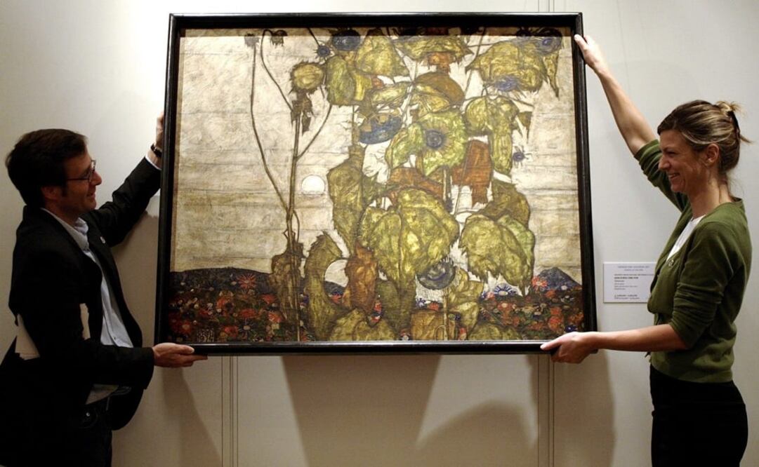 Imagen de archivo de dos personas sosteniendo el cuadro "Girasoles Marchitos", de Egon Schiele. La obra fue confiscada al coleccionista Karl Grunwald en 1942, durante el régimen nazi.  Foto: EFE/Martial Trezzini, archivo