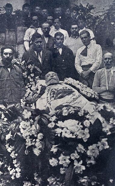 Fotografía extraída de EL UNIVERSAL ILUSTRADO, en su edición del 27 de mayo de 1920. Se ve el cuerpo del presidente Venustiano Carranza, envuelto con la bandera nacional, con la guardia de sus hombres y habitantes de Villa Juárez, Puebla. Foto: Hemeroteca EL UNIVERSAL.