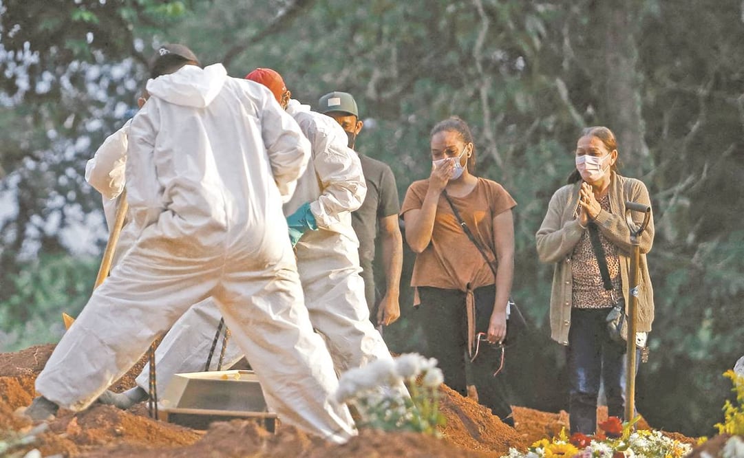 Brasileños esperan en el cementerio a que su familiar sea enterrado por personal con equipo de protegido. Brasil suma 381 mil 475 muertos por la enfermedad. Foto: Miguel Schincariol/ AFP.