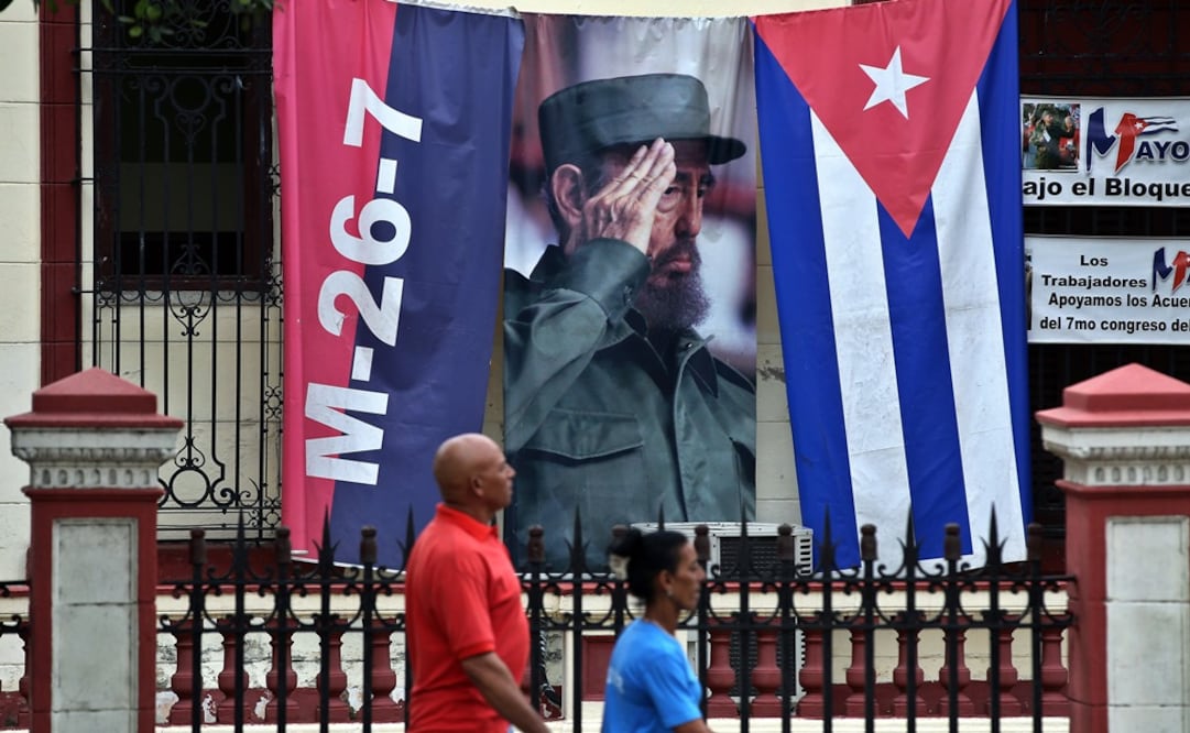 Dos personas caminan junto a un lienzo con la imagen del fallecido líder cubano Fidel Castro en una calle de La Habana (Foto: EFE)