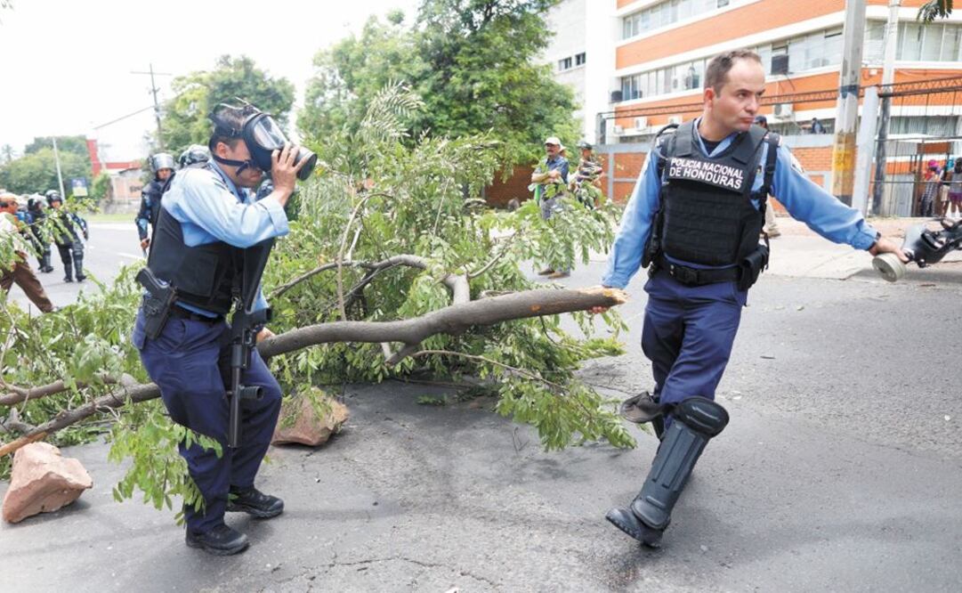 Policías limpian las calles de Tegucigalpa, tras la protestas contra el gobierno. Foto: ELMER MARTÍNEZ. AP