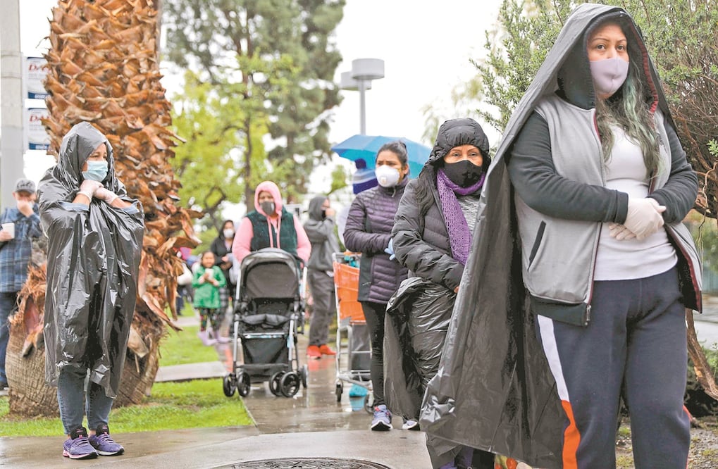 En Van Nuys, California, decenas de personas con falta de recursos, algunas con una bolsa encima para protegerse de la lluvia, recibieron comida en el banco de alimentos ante la pandemia de coronavirus. Foto: MARIO TAMA. AFP