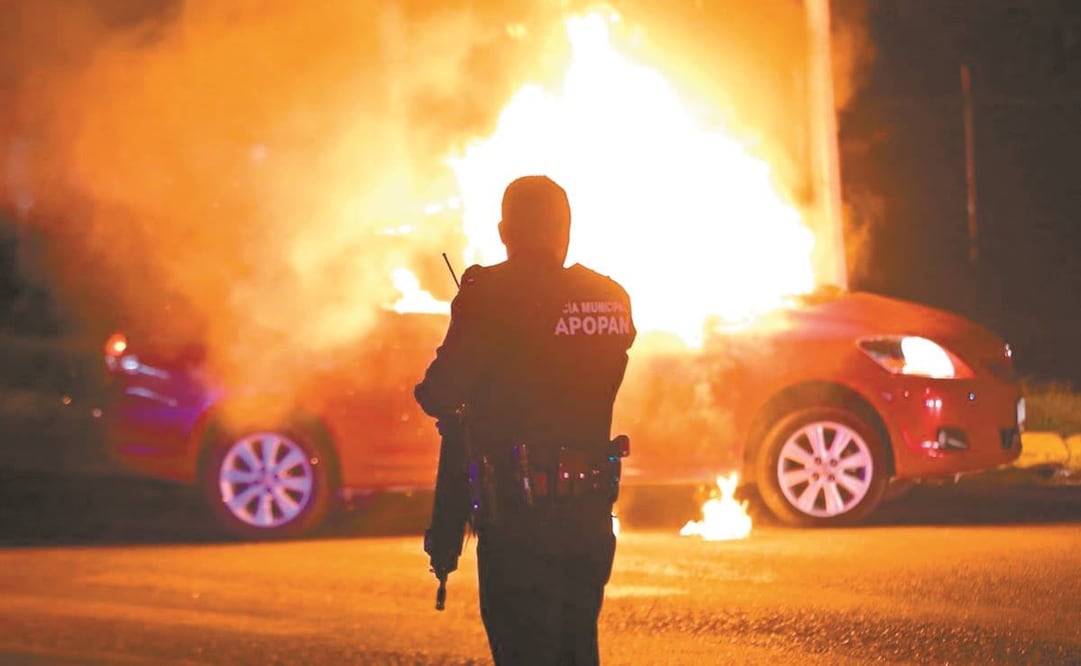 Un policía resguarda la zona en la que un grupo criminal incendió un vehículo, en Zapopan, Jalisco, en agosto de 2022.