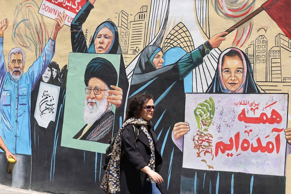 Una mujer iraní pasa junto a un mural antiestadounidense y antiisraelí, en Teherán.  FOTO: ATTA KENARE. AFP