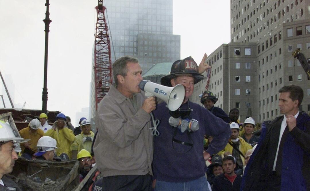 El entonces presidente estadounidense George W. Bush (izq.), de pie junto al bombero retirado Bob Beckwith, de 69 años, habla con voluntarios y bomberos mientras examina los daños en el sitio del World Trade Center en esta fotografía de archivo del 14 de septiembre de 2001 en Nueva York. Foto: AFP