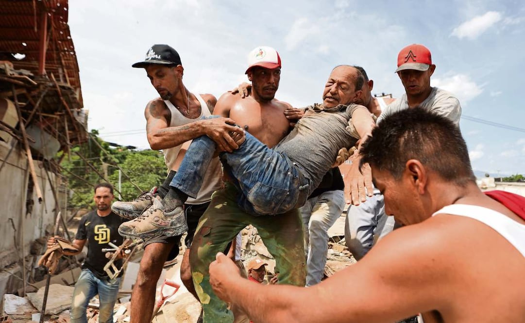 Vecinos con un hombre rescatado de entre los escombros de un edificio derrumbado, al día siguiente de los terremotos que azotaron La Guaira, Venezuela. Foto: Pedro Mattey / AP