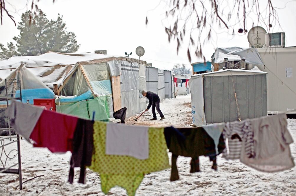 Un refugiado sirio quita la nieve que rodea su tienda de campaña, en el campamento de Ritsona, al norte de Atenas. La Comisión Europea dijo que la situación de los migrantes debido a la ola de frío es “insostenible”. (MUHAMMED MUHEISEN. AP)